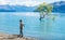 Shot of young man wearing hoodies and standing on the bank of lake Wanaka with iconic lone tree. South island of New Zealand.