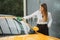 Shot of young woman in business outfit, shirt and trousers cleaning windscreen of sport car