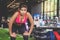 Shot of young woman in sportswear bending with her hands on knees at the gym. Fitness woman looking tired after exercising at gym