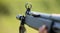 Shotgun in man` s hand. Front side of weapon with close up view on blurred nature background.