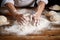 shots of hands kneading dough in a bakery, flour dusted on wooden table