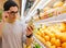 This should be fine. Handsome young men holding pear and shopping bag while standing in a food store