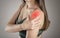 Shoulder pain in a woman. Highlighted in red. On a gray background. Close up