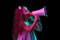 Shouting at megaphone. Stylish little girl, beginner fashion model posing isolated over dark background in neon light