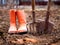 Shovel, pitchfork and orange rubber boots in spring garden