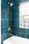 A shower detail with vertical blue subway tiles.