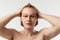 After shower, getting ready. Portrait of young handsome redhead man posing shirtless over grey studio background