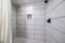 Shower stall with mosaic tiles flooring and marble tiles surround with black grout