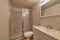 Shower stall with sliding glass door beside toilet and sink on white countertop