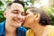 Showering him with love. a young woman kissing her husband on the cheek while in the park.