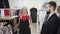 Showing clothing to a husband. Beautiful blonde-haired stylish beaming glowing alluring woman showing the black dress