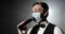 Showman host of event in medical mask speaks at microphone at concert on stage.