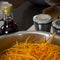 Shredded carrots in a professional large steel pan. Sauce and sp