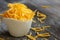 Shredded cheddar cheese in white cup close up view