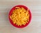 Shredded sharp cheddar cheese in red bowl