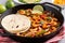 shrimp fajitas in a pan with lime wedges