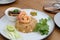 Shrimp fried rice with vegetables on the white dish on wooden table.