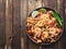 Shrimp pad thai on plate in flat lay composition with copy space atop rustic wooden table