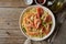 Shrimp, pasta tagliatelle, green peas, dill. White plate on old rustic wooden table, top view, copy space