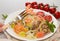 Shrimps on fork above plate. Pasta tagliatelle with grilled shrimps, salmon fish, gouda cheese, serving with tomato cherry, leek