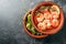 Shrimps and fried pimientos or padron peppers in stacked tapa bowls, traditional Spanish appetizer on a dark gray slate background
