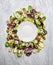 Shrimps salad with lettuce and tomatoes around white empty plate, on light gray wooden background, top view