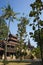 Shwe In Bin teak monastery with intricate detailed wood carving view from between tall trees. Mandalay, Myanmar