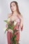 Shy caucasian girl with big eyes stands in a velvet pink dress and holds a white Lily in her hand as a symbol of innocence and pur