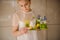 Shy girl holding a composition plate with white and yellow toy chicken,green moss and blue muscari