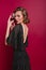 Shy girl in trendy party dress looking over shoulder standing on dark background. Studio shot of sensual brown-haired