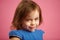 Shy little girl with cute look, close-up portrait on pink isolated background.