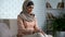 Shy muslim female sitting on sofa at home, waiting husband from work, marriage