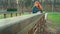 Shy old, red-haired woman leaning on handhold in park. Charming pretty woman thoughtfully