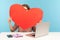 Shy woman hiding face behind huge red paper heart and peeking curious, holding symbol of love, romantic feelings