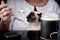 A Siamese cat in a woman`s arms is eating sour cream from a spoon.