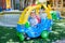 Sian 1 year old toddler baby boy child riding on a colorful small toy car at play ground in the day time