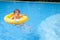 Sian 2 years old toddler boy child having fun playing with inflatable swim ring in outdoor swimming pool on hot summer day