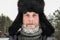 Siberian Russian man with a beard in hoarfrost in freezing cold in the winter freezes and wears a hat with a earflap