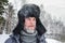 Siberian Russian man with a beard in hoarfrost in freezing cold in the winter freezes and wears a hat with a earflap