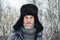 Siberian Russian man with a beard in hoarfrost in freezing cold in the winter freezes and wears a hat with a earflap