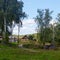 Siberian village landscape with a turn of rural road at the slides with houses and trees, birches green field.