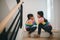 Sibling Asian girls playing rock paper scissors hand game. children sitting on stairs at home playing together