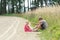 Sibling children playing in dust sitting on summer dirt road