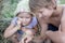 Sibling girl and boy holding green praying mantis in summer field