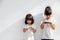 Sibling girls watching their smartphones on white background. Social concept about new technology people addiction