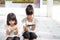 Sibling girls watching their smartphones on white background. Social concept about new technology people addiction