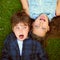 Sibling silliness. High angle shot of a young brother and sister pulling faces while lying on the grass outside.