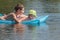 Siblings floating on inflatable azure pool air mat in summer pond outdoor