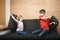 Siblings having pillow fight on a couch confined at home during self-isolation