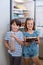 Siblings holding cake and bottle in kitchen